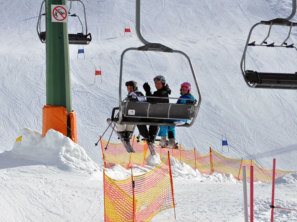 Sessellift über der Piste mit orangefarbenem Sicherheitsnetz.